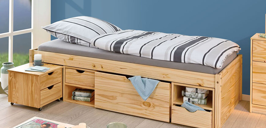 Bett aus Holz mit gestreifter Bettwäsche und vielen Schubladen