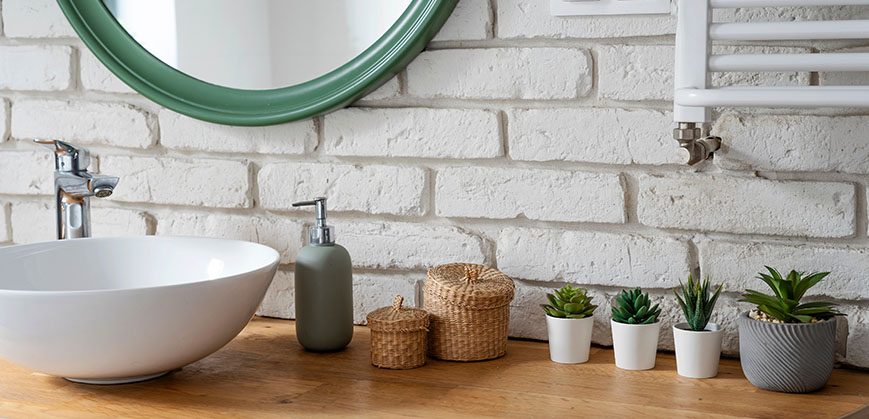 Hölzernes Regal mit Spiegel, weißem Waschbecken und kleinen Pflanzen